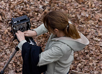 © Robert Buncher. Overhead view of Karen Antonelli setting up a Graflex Crown Graphic 4x5 camera in a wood